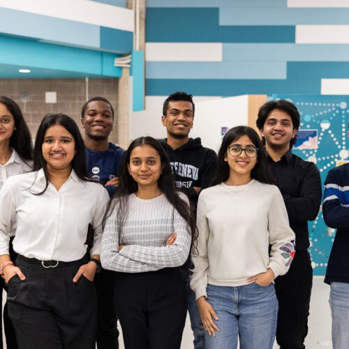 Student workers from the Math and Science Learning center stand in the center of the space and smile