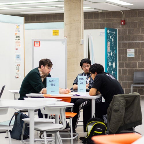 Students sitting with with a teaching assistant and studying math