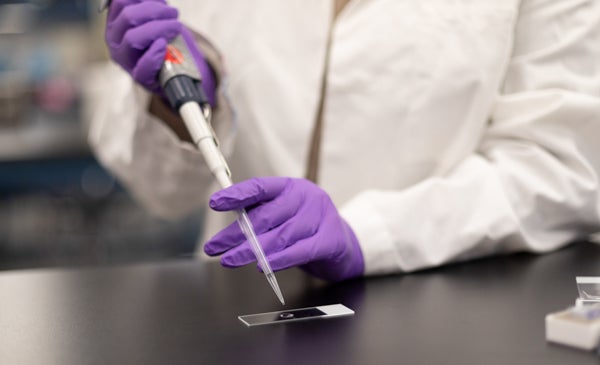 Student doing titrations wearing purple gloves and white lab coat